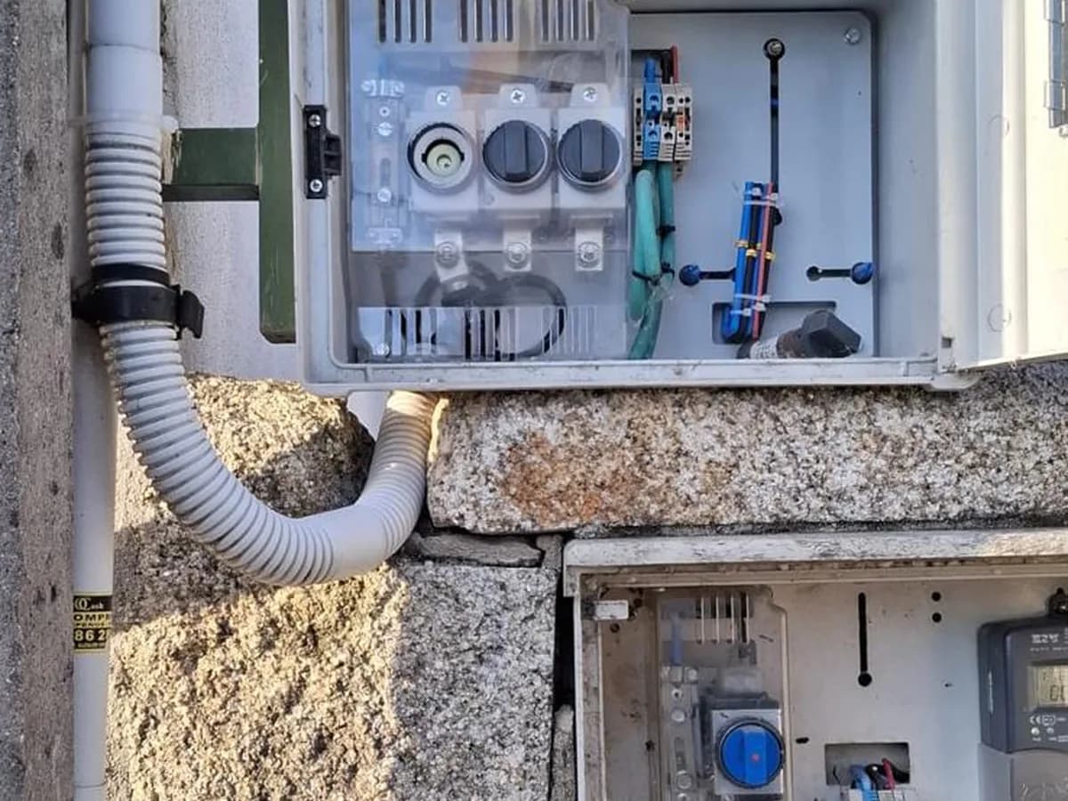Caja general de protección abierta en una fachada de piedra, con los fusibles a la vista
